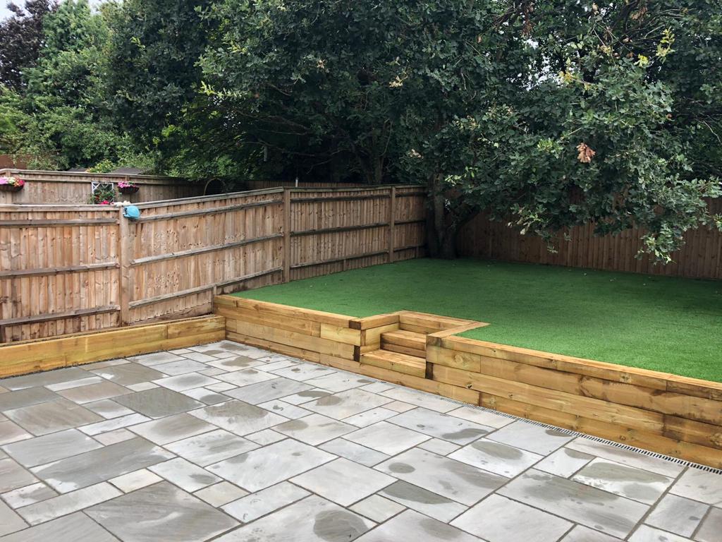 back garden with raised lawn and hard stone patio